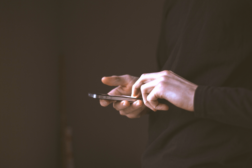 Image of hands holding and typing a message on an iPhone.